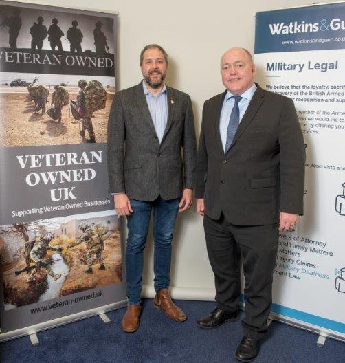 Scott Johnson (left) and Clive Thomas (right) stand side by side in front of a Veteran Owned UK sign and a Watkins & Gunn sign.